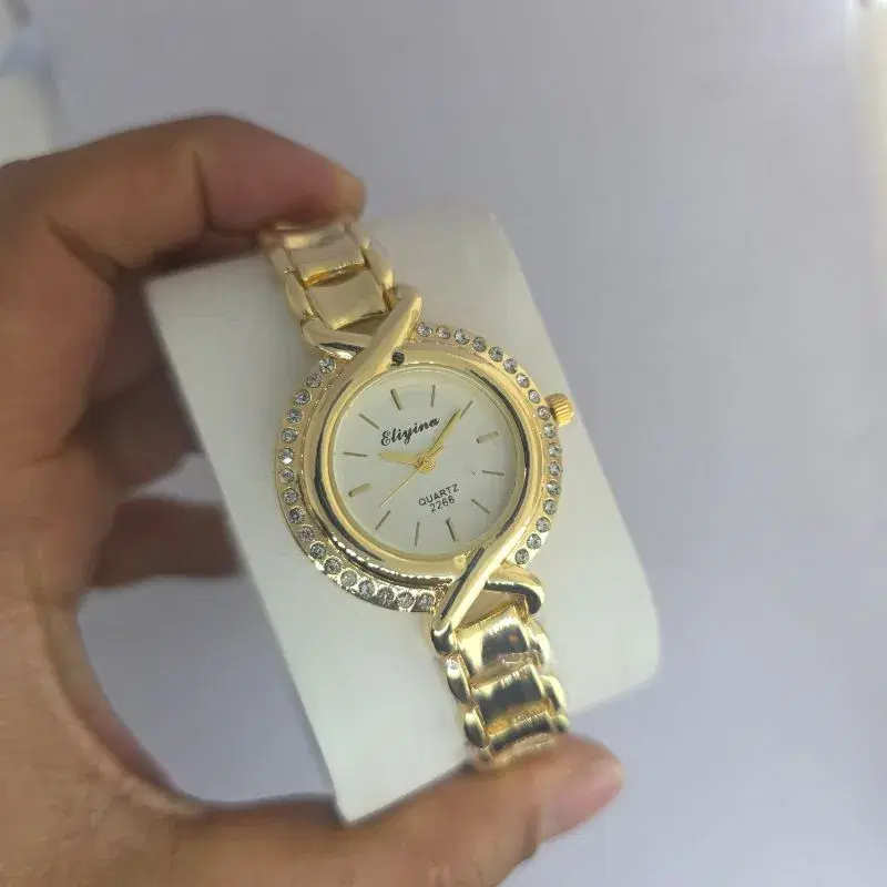 Eliyina quartz watch for women features a golden stainless steel bracelet and a crystal-encrusted round dial.