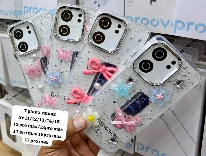 decorative, clear phone cases featuring 3D bow, heart, and flower charms with silver glitter accents, designed for various iPhone models.