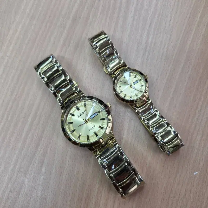 gold-toned Rado-style quartz couple's watches with stainless steel bands.