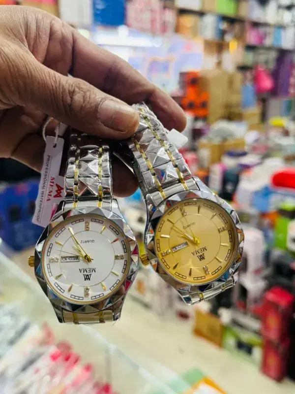 MEMA branded quartz watch with a gold-colored dial, a date/week display, and a two-tone stainless steel strap.