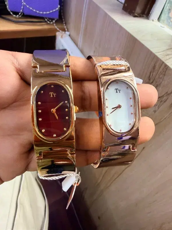 gold-tone Tt brand wristwatches feature a distinct oval dial design and a wide, metallic band