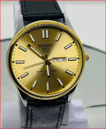 eiko 5 wristwatch features a vibrant gold dial with luminous markers and a classic black leather strap